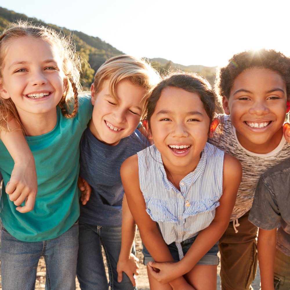 Group of mixed race children standing together laughing and smiling enjoying their childhood